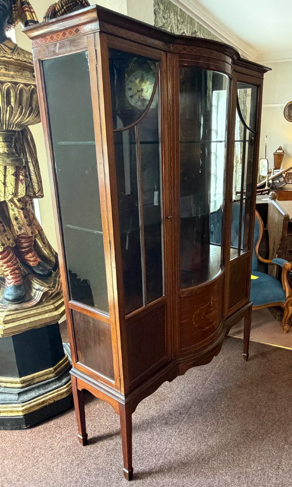 A late Victorian mahogany bow-front display cabinet featuring glazed doors, detailed marquetry inlay, and raised square tapered legs. View IV