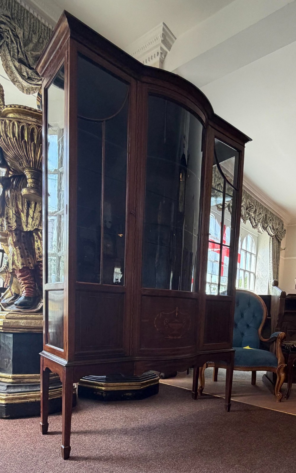 A late Victorian mahogany bow-front display cabinet featuring glazed doors, detailed marquetry inlay, and raised square tapered legs. View VI