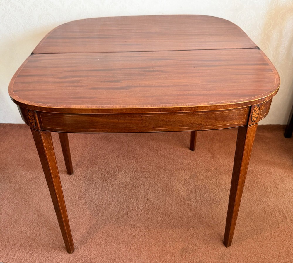 A Sheraton period mahogany tea table with a semi-circular folding top, string inlay along the apron, and slender square tapered legs. View IV