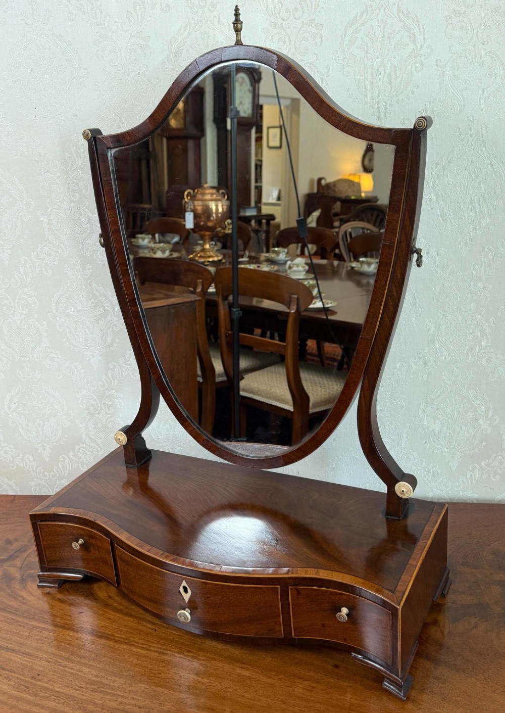 A Regency mahogany box dressing mirror with an oval swing frame supported above a serpentine base with three drawers.