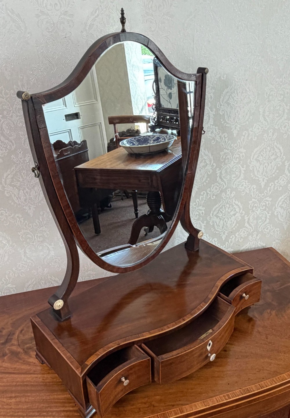 A Regency mahogany box dressing mirror with an oval swing frame supported above a serpentine base with three drawers. View III