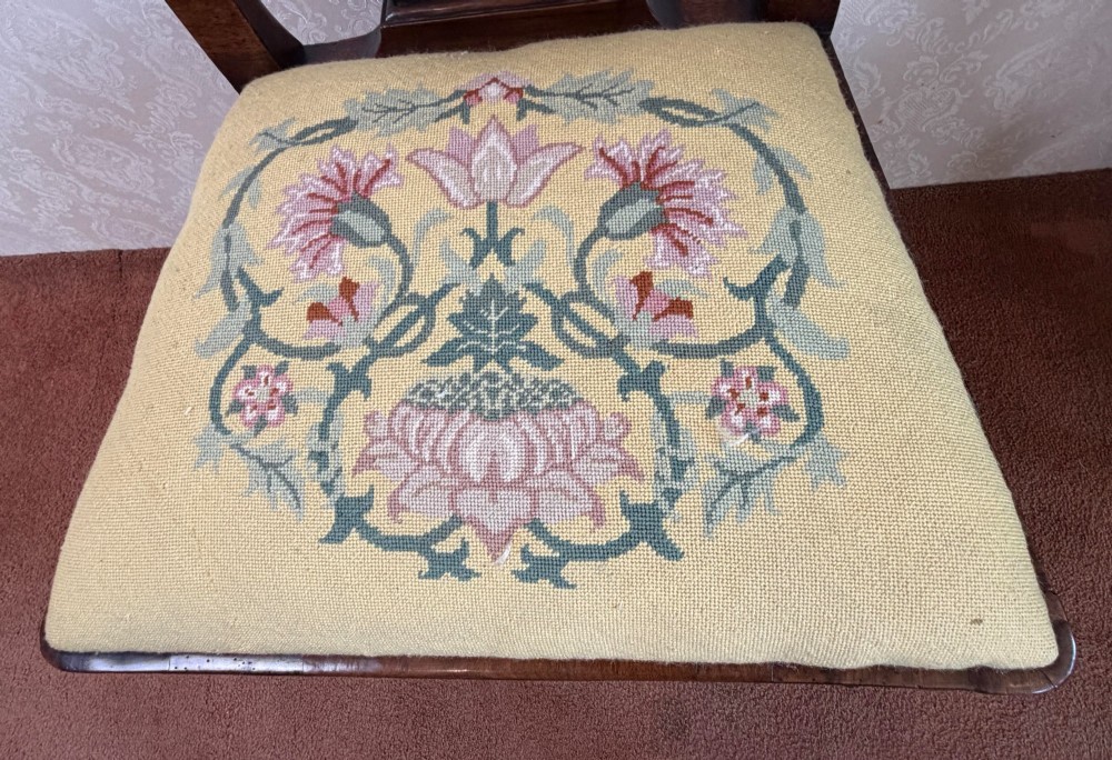 An early 18th-century walnut side chair featuring a carved pierced splat back, shaped apron, cabriole front legs, and an embroidered drop-in seat pad. View V