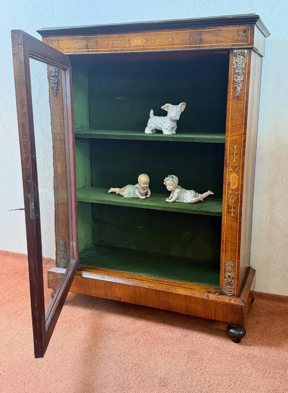 A Victorian burr walnut pier cabinet with floral marquetry inlay, ornate gilt brass mounts, and a single glazed door disclosing velvet-lined shelving. View II