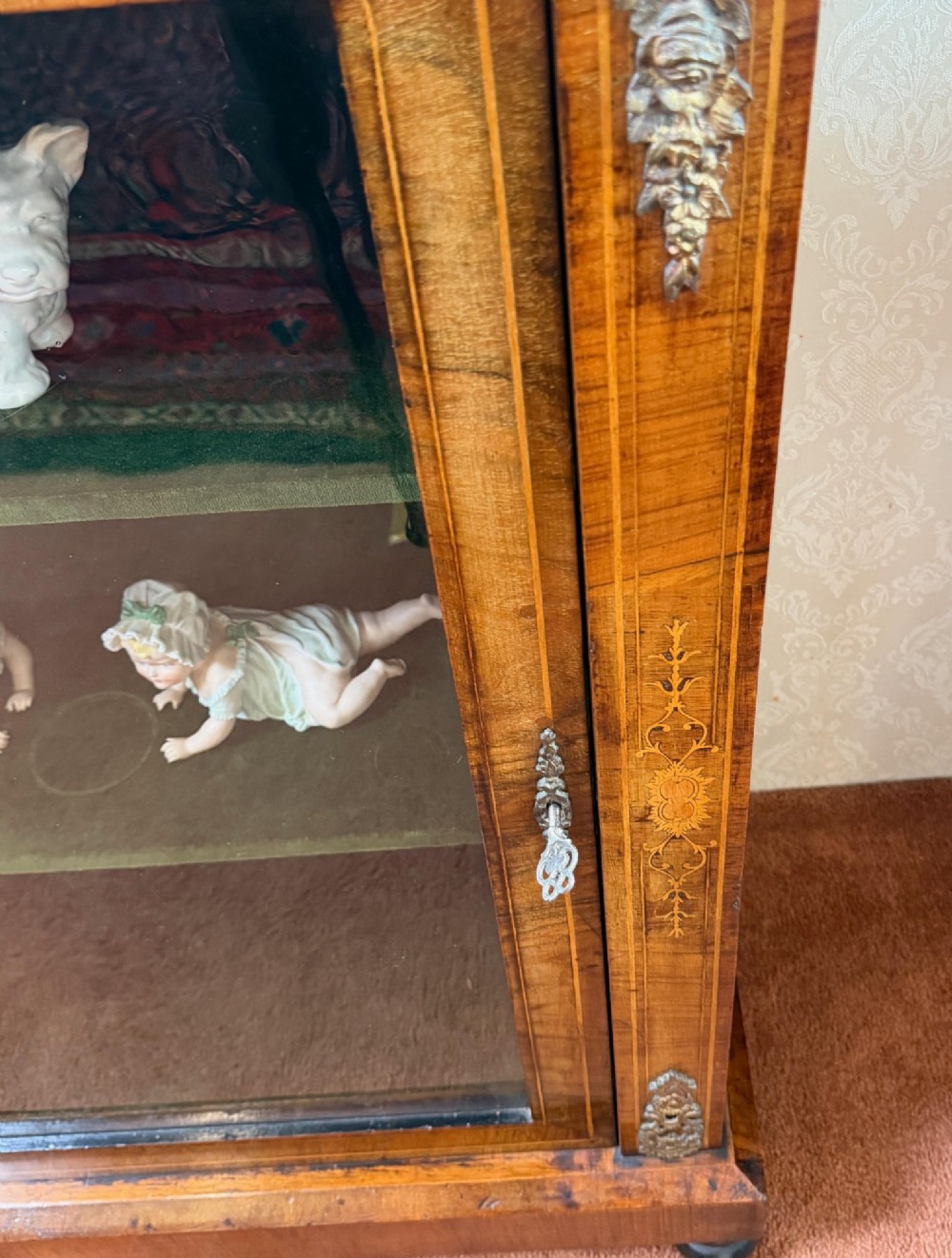 A Victorian burr walnut pier cabinet with floral marquetry inlay, ornate gilt brass mounts, and a single glazed door disclosing velvet-lined shelving. View V