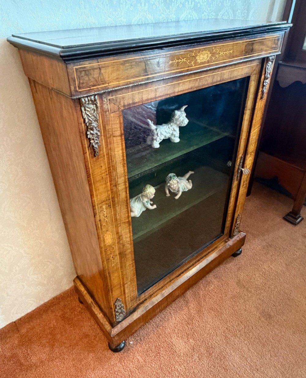A Victorian burr walnut pier cabinet with floral marquetry inlay, ornate gilt brass mounts, and a single glazed door disclosing velvet-lined shelving. View VII