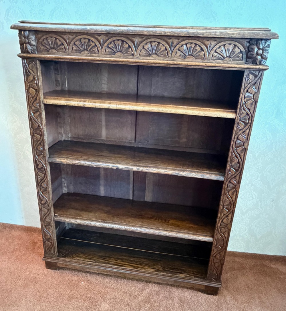 Late 19th-century dark oak open bookcase featuring hand-carved floral stiles, a lunette frieze, and four open shelves.