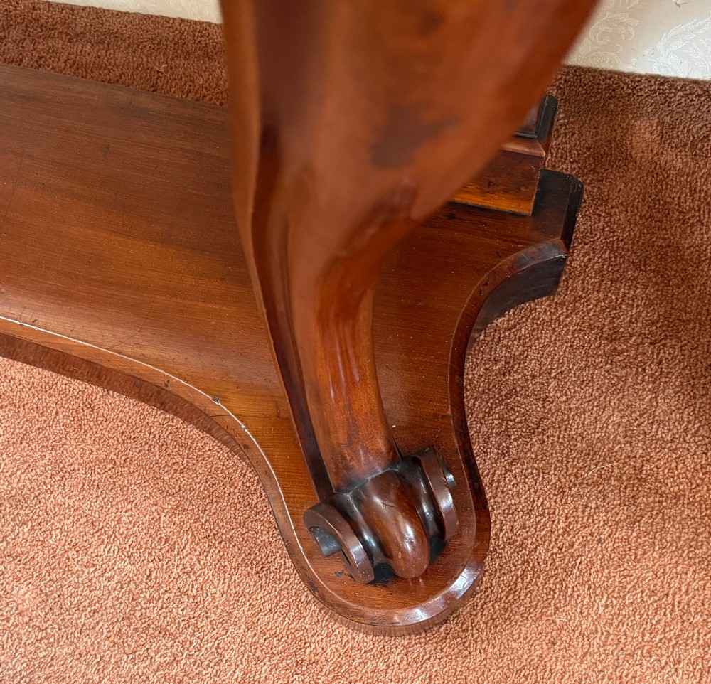 A Victorian mahogany serpentine console table featuring carved S-scroll legs, a low splashback upstand, and a shaped plinth base. View II