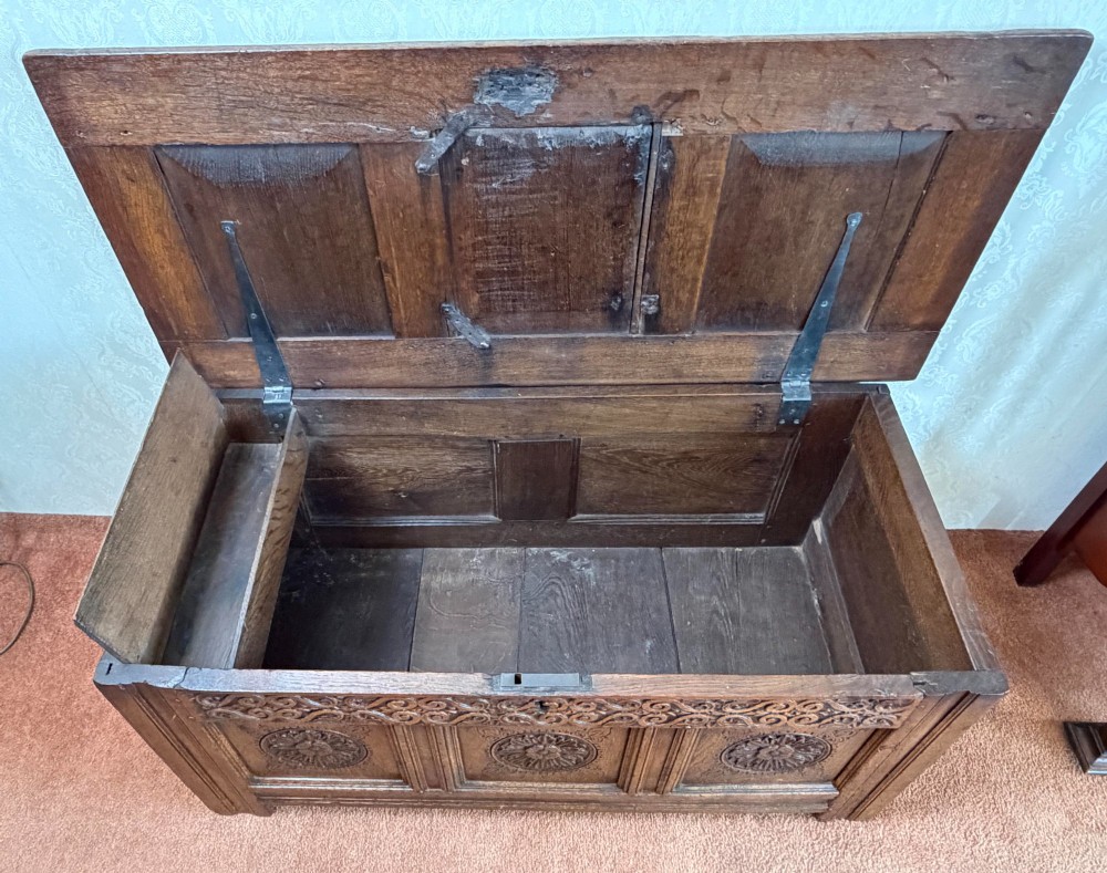 A 17th-century English oak coffer featuring a three-panel front carved with floral rosettes, an upper carved frieze, and a panelled lid. View III