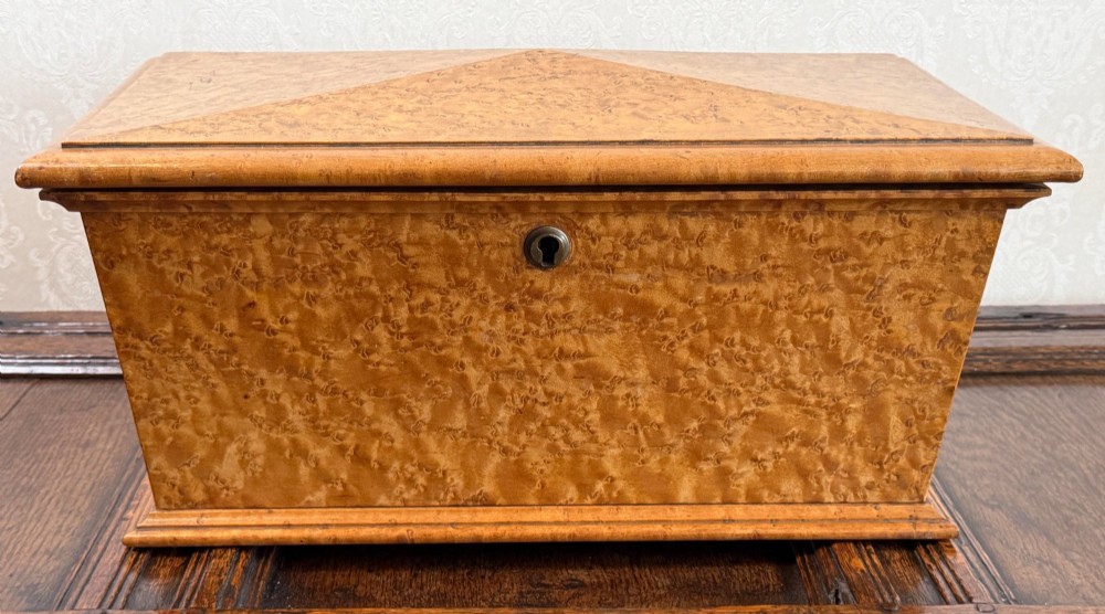 An early nineteenth-century William IV birdseye maple tea caddy featuring a faceted lid and brass keyhole escutcheon.