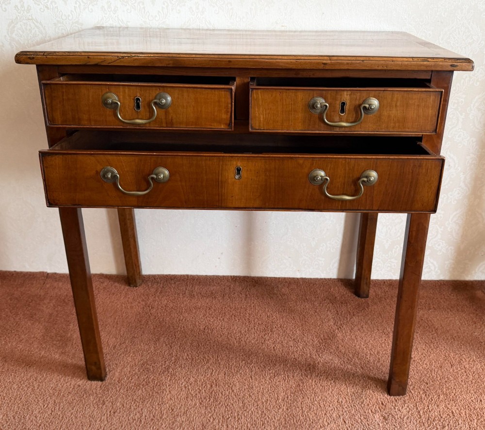 An antique English walnut lowboy featuring two small upper drawers above one long drawer, mounted with brass drop handles on four legs. View III