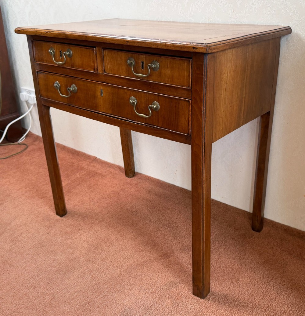 An antique English walnut lowboy featuring two small upper drawers above one long drawer, mounted with brass drop handles on four legs. View VI