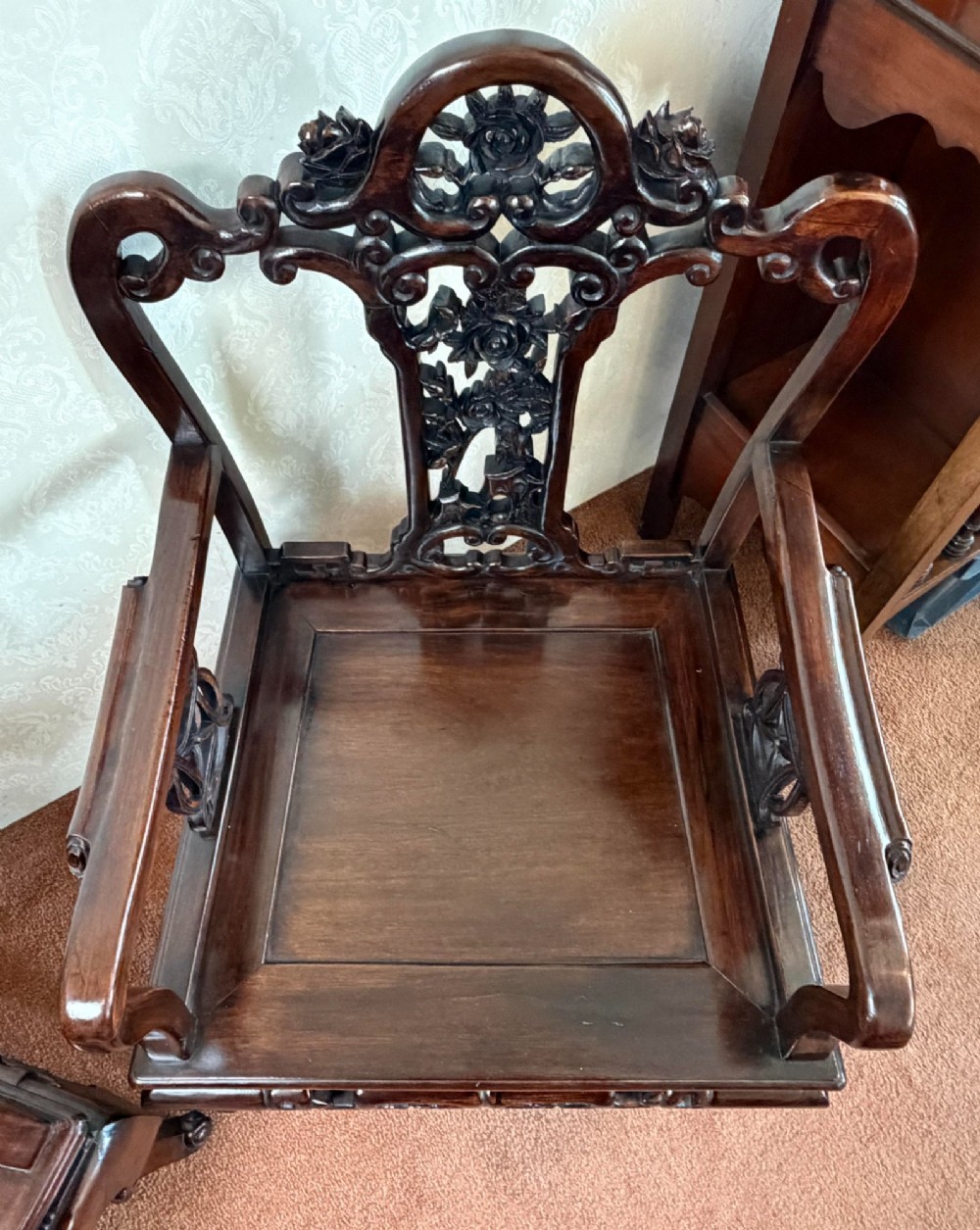 A pair of dark polished hardwood armchairs featuring intricate openwork floral carvings on the splat and decorative carved aprons. View IV