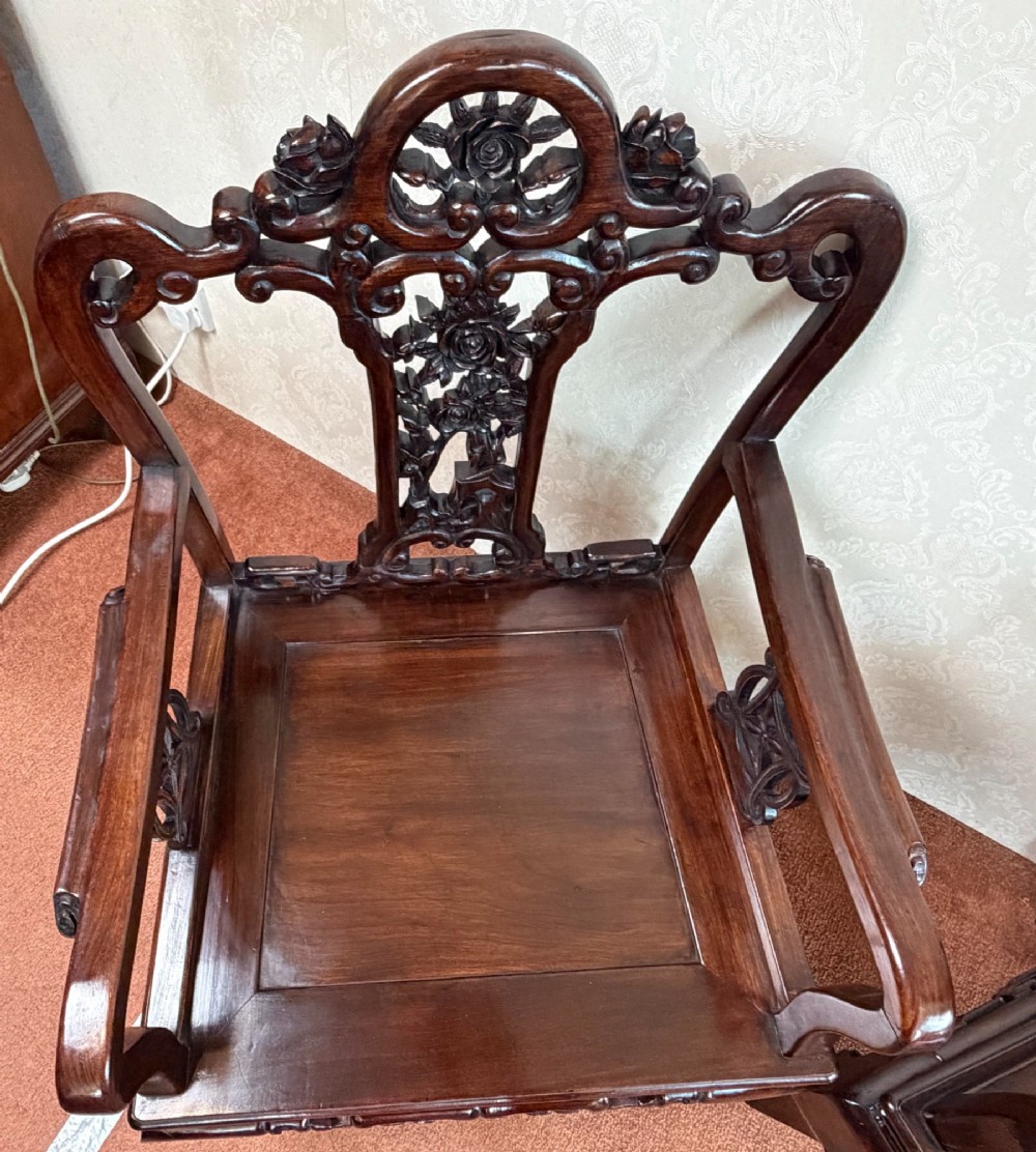 A pair of dark polished hardwood armchairs featuring intricate openwork floral carvings on the splat and decorative carved aprons. View V