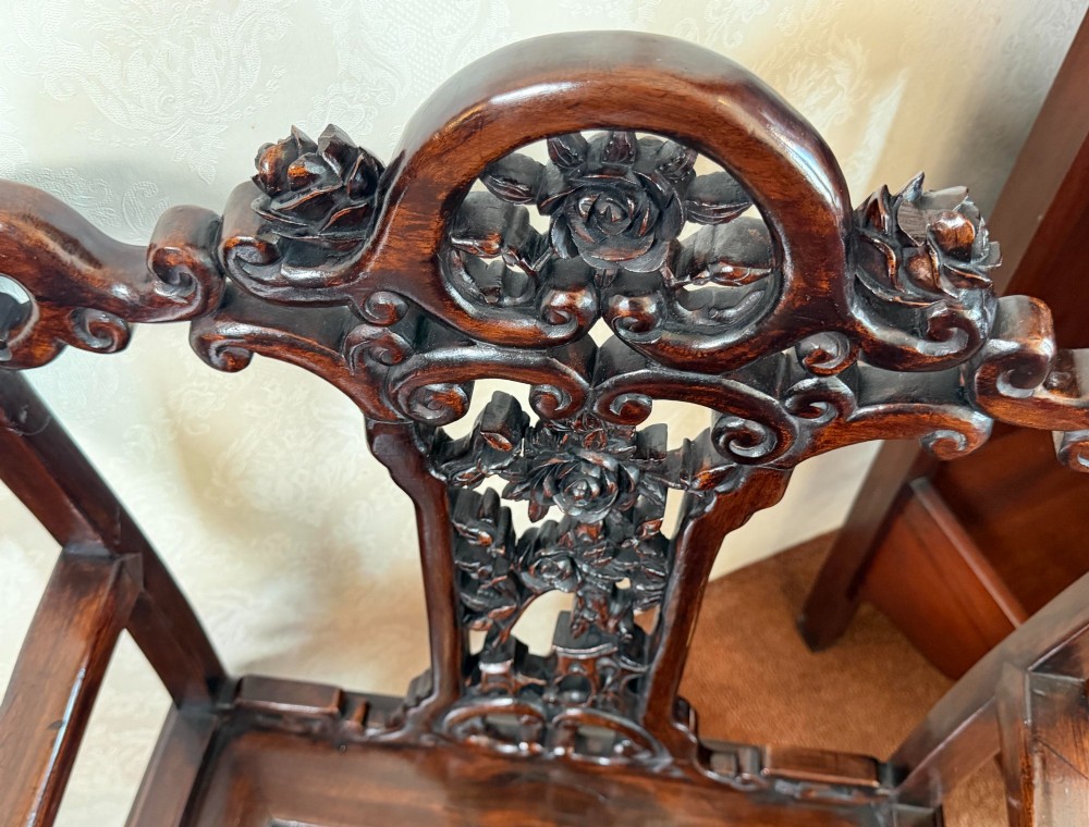 A pair of dark polished hardwood armchairs featuring intricate openwork floral carvings on the splat and decorative carved aprons. View VII