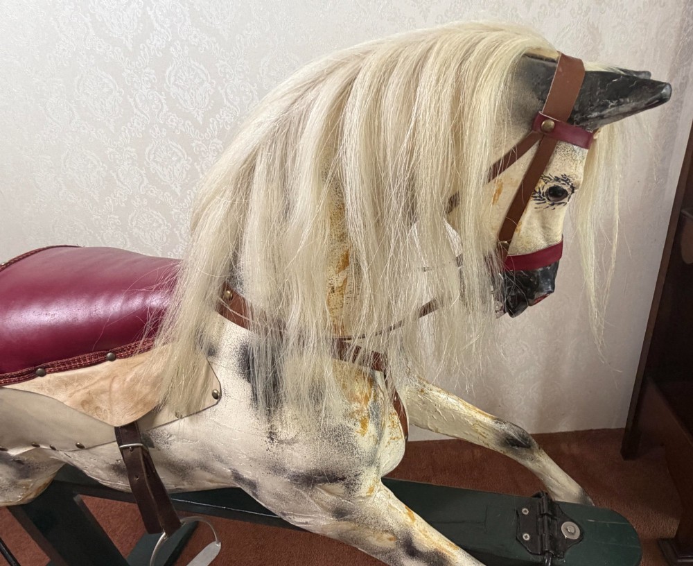 A 19th-century carved wooden dappled grey rocking horse with a leather saddle, horsehair mane, and dark green painted glider stand. View II