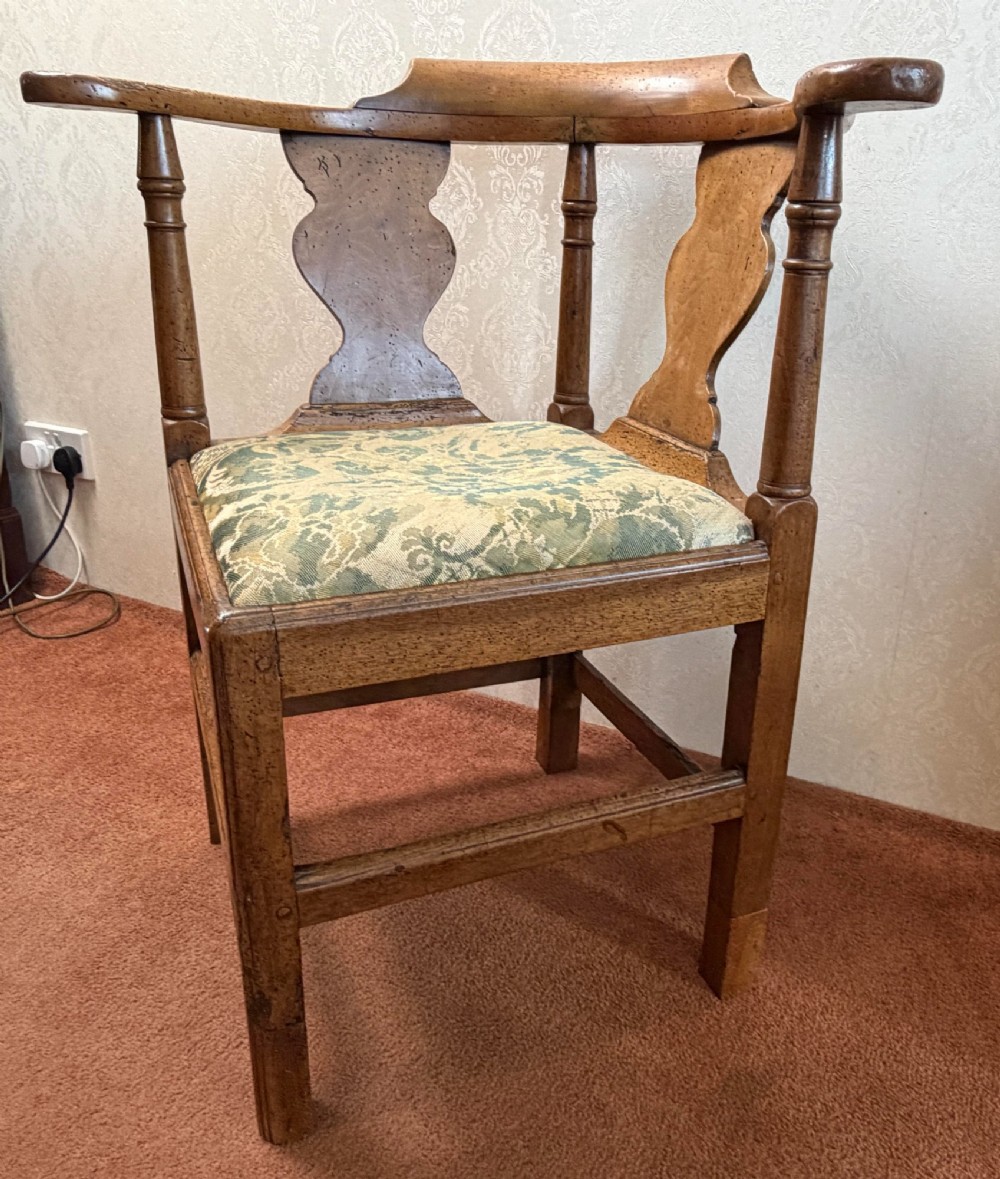 An 18th-century oak corner chair featuring turned supports, two vase-shaped back splats, a curved top rail, and a patterned green fabric drop-in seat. View II