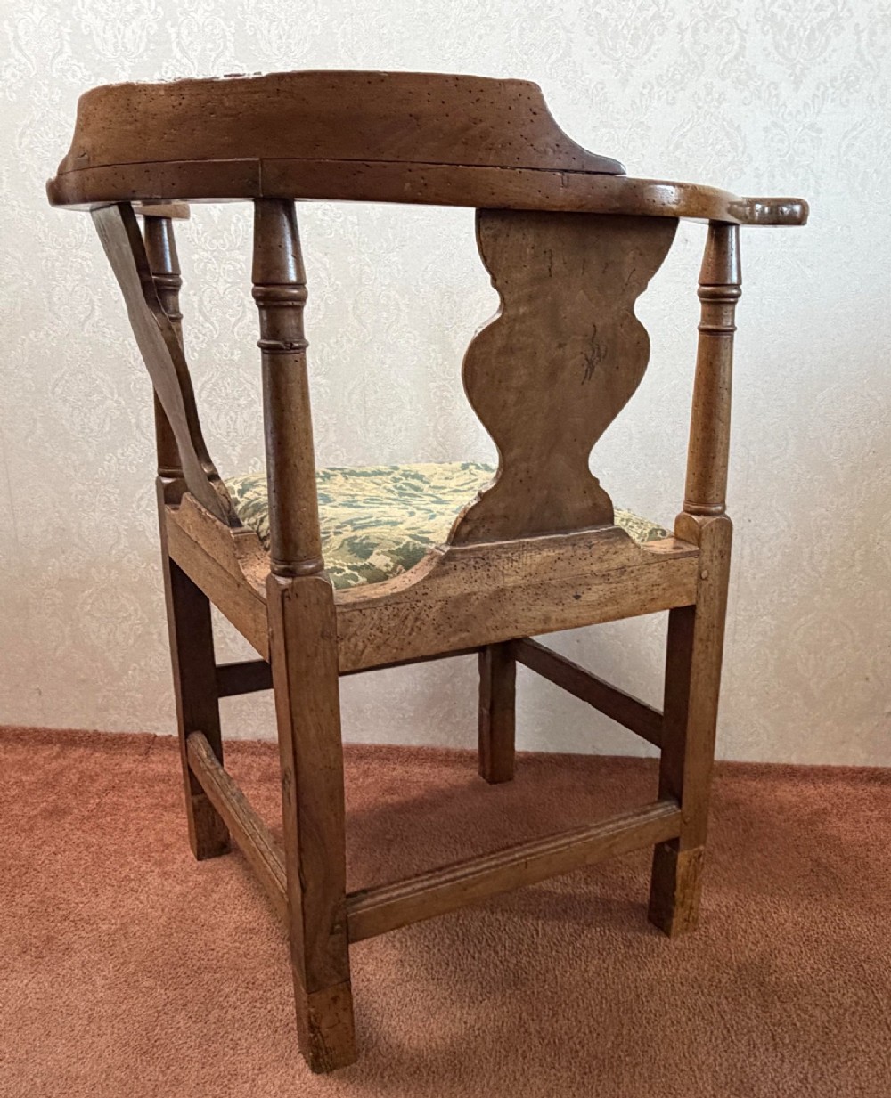 An 18th-century oak corner chair featuring turned supports, two vase-shaped back splats, a curved top rail, and a patterned green fabric drop-in seat. View VI
