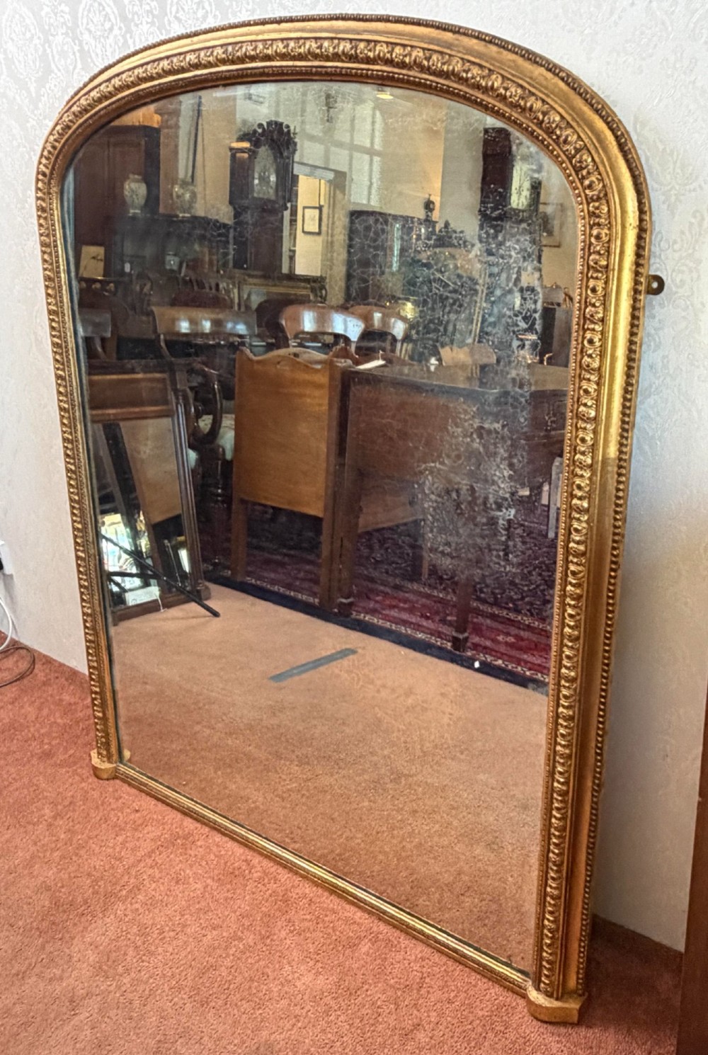 A Victorian arched overmantel mirror featuring a gilded wood frame with beaded moulding and foxed glass plate. View IV