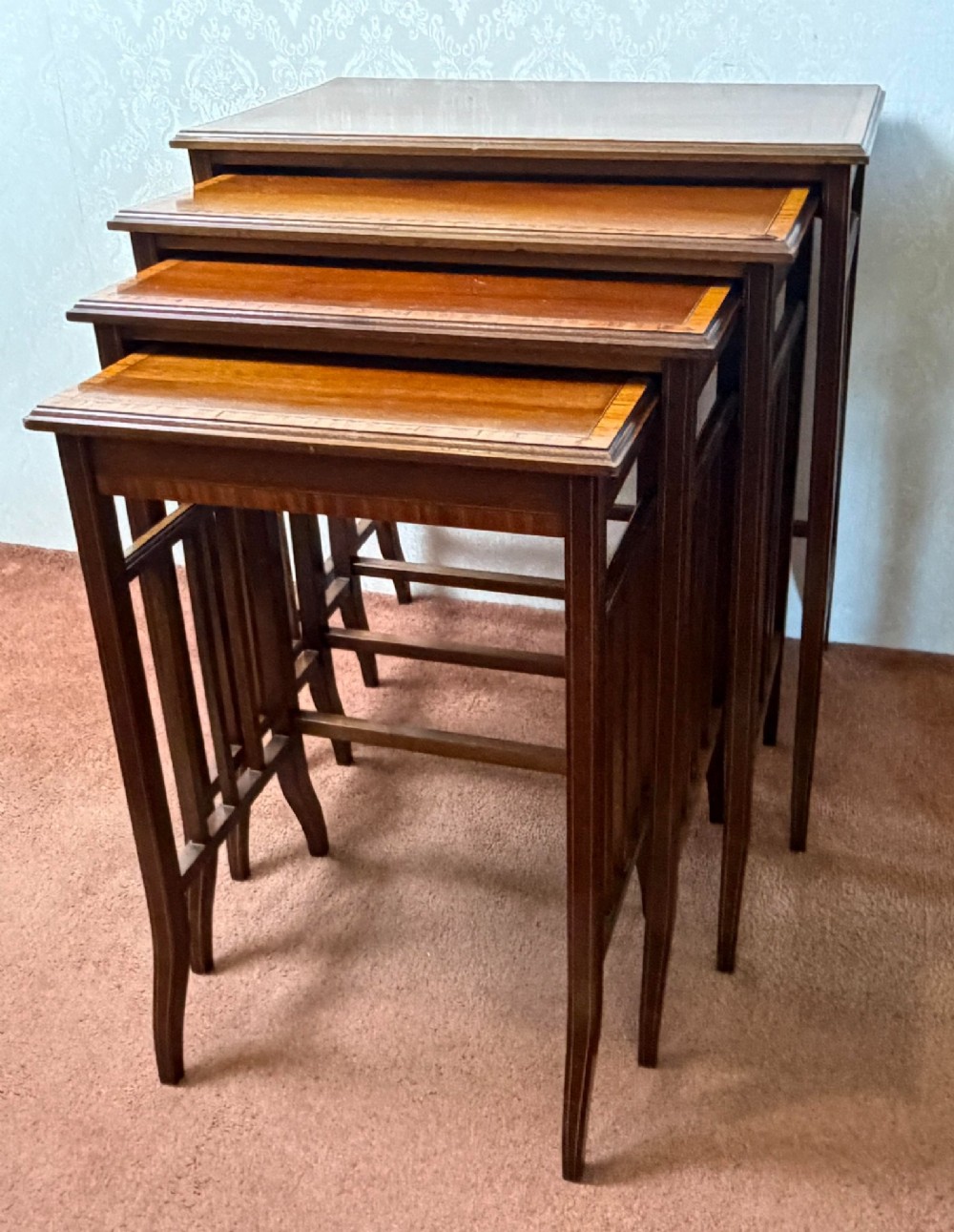 A set of four nesting mahogany tables featuring rectangular tops with satinwood crossbanding and square tapered legs. View II