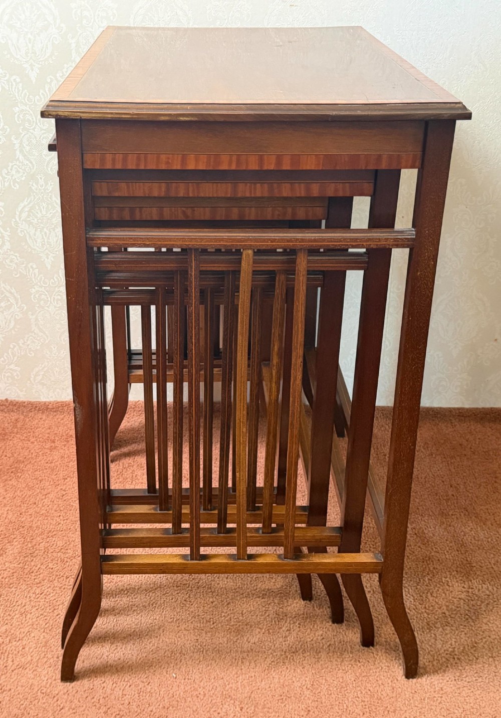 A set of four nesting mahogany tables featuring rectangular tops with satinwood crossbanding and square tapered legs. View V