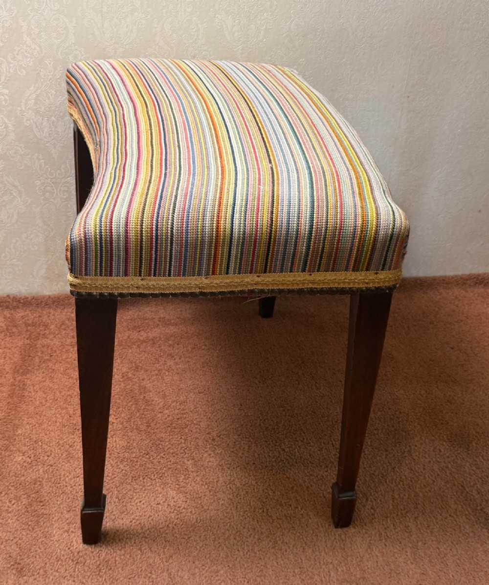 A late 18th-century mahogany stool with square tapering legs and a seat upholstered in multi-coloured vertical striped fabric with braided trim.
