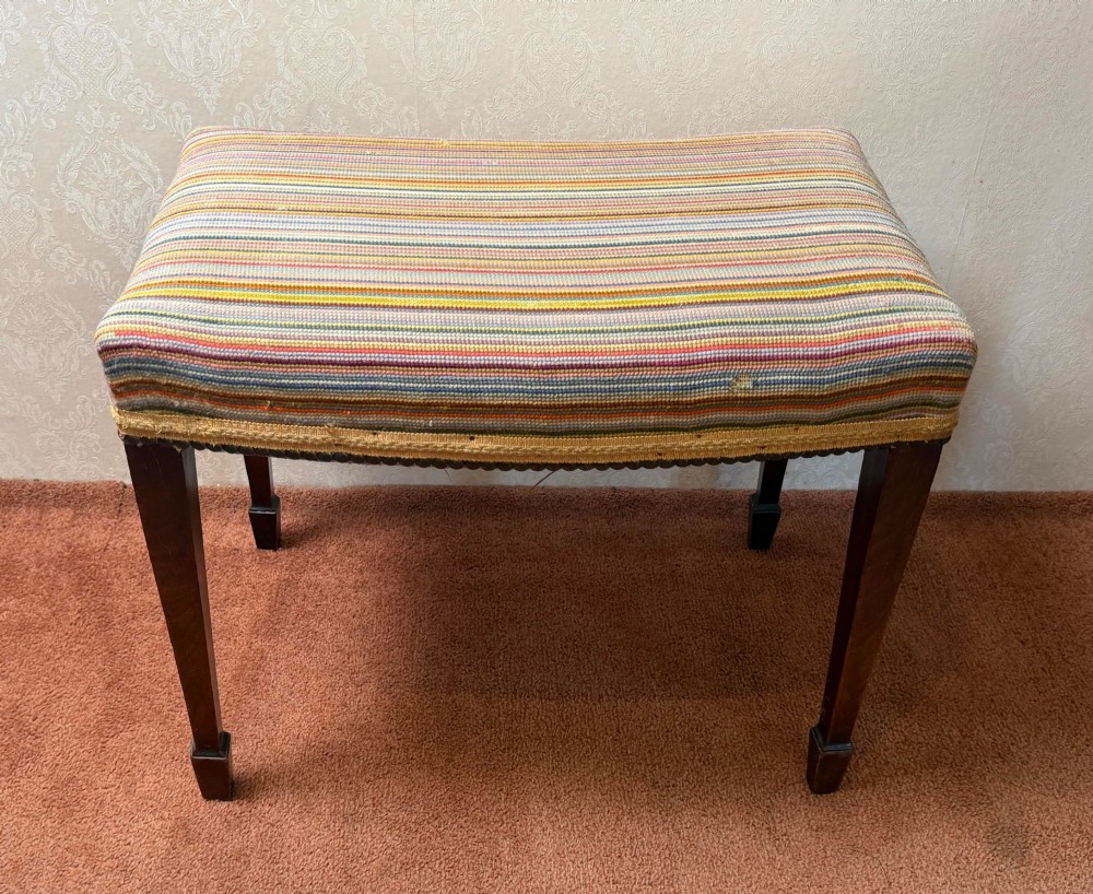 A late 18th-century mahogany stool with square tapering legs and a seat upholstered in multi-coloured vertical striped fabric with braided trim. View V