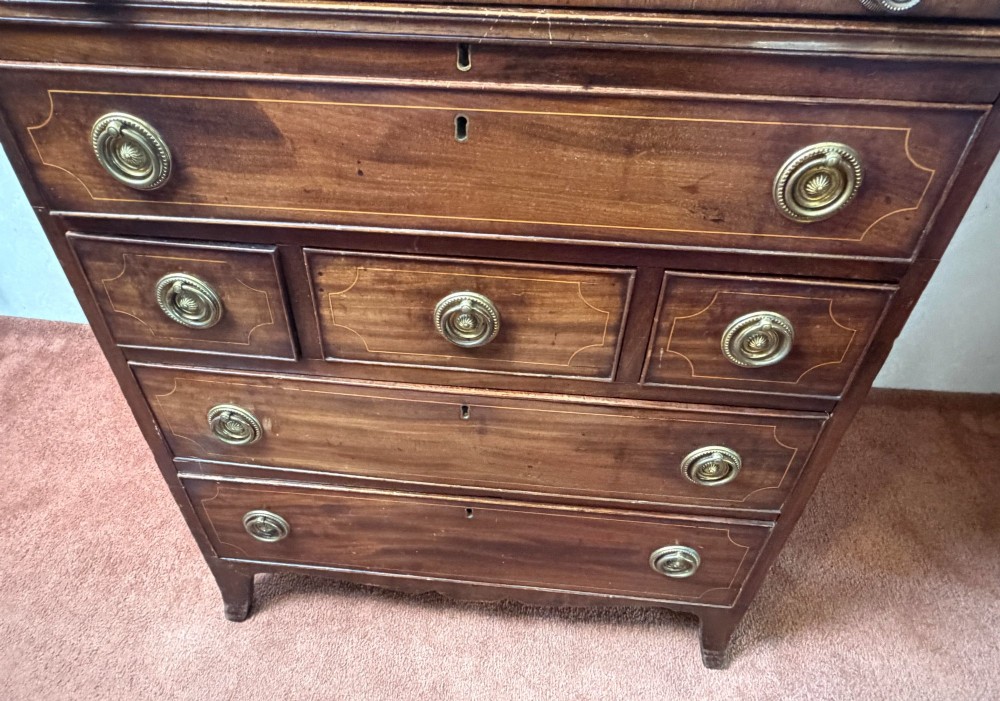 A Georgian mahogany tambour writing desk with boxwood line inlay, circular brass ring handles, and multiple storage drawers beneath a curved roll-top front. View III