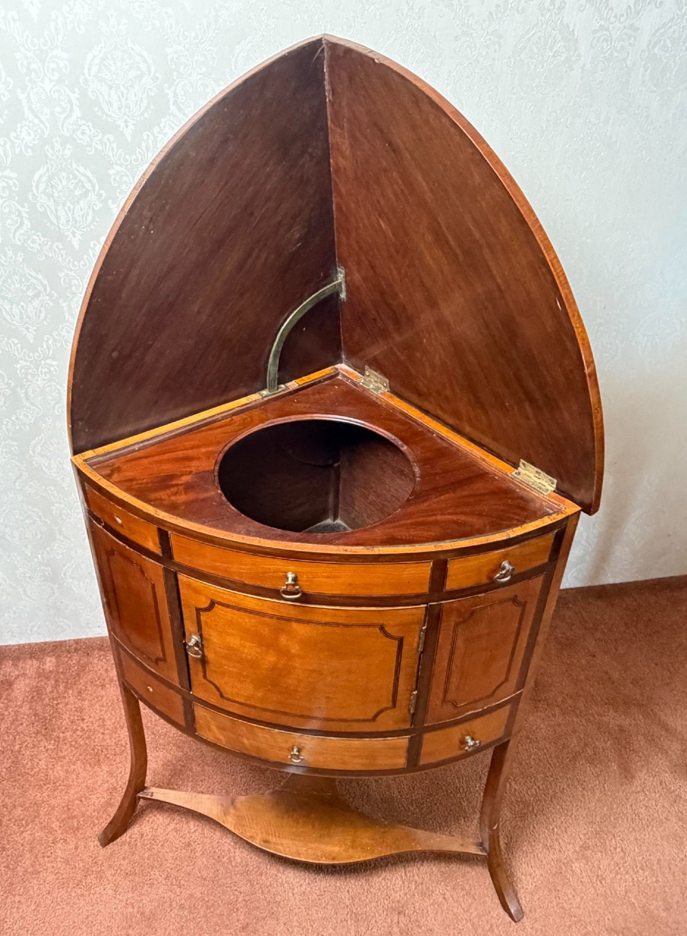 A Georgian satinwood corner washstand with dark timber crossbanding, a central cupboard door, and splayed legs. View V