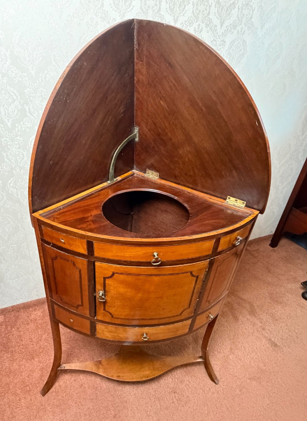 A Georgian satinwood corner washstand with dark timber crossbanding, a central cupboard door, and splayed legs. View VI