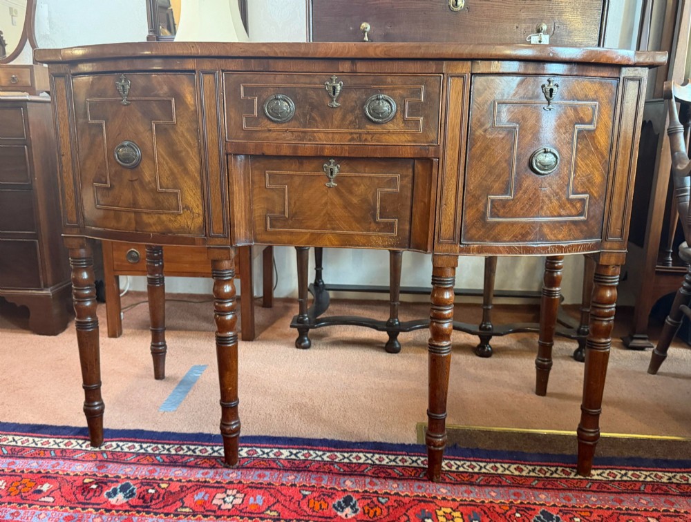 A Regency style mahogany bow-front sideboard featuring geometric string inlay, central drawers flanked by cupboards, brass drop handles, and turned legs. View VII