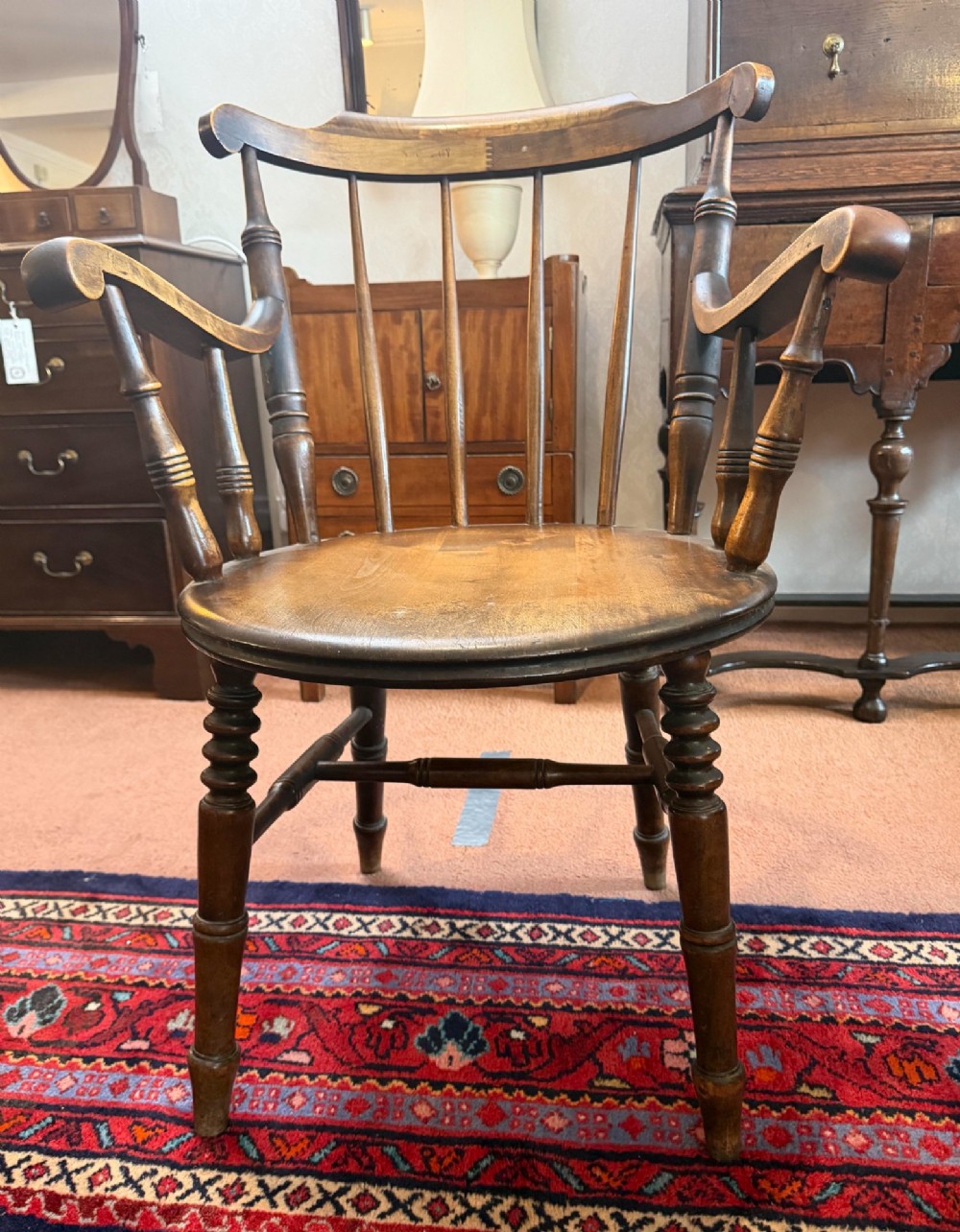 A Victorian ash wooden desk chair featuring turned legs, a contoured seat, curved armrests, and a spindle backrest.