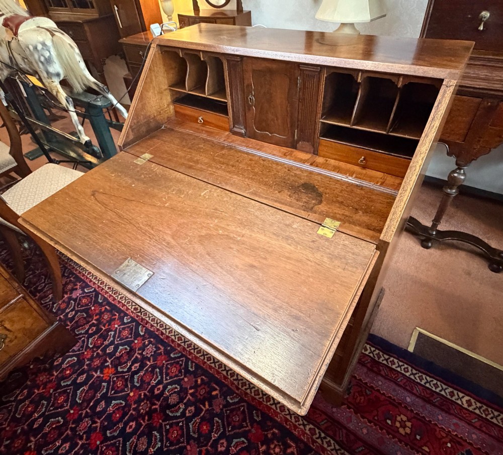 A George III mahogany bureau featuring a slant-front writing slope above two short and three long drawers with brass swan-neck handles, resting on bracket feet. View VI