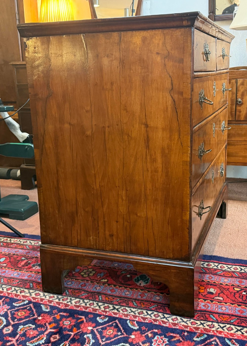An antique burr walnut chest of drawers featuring two short over three long drawers with ornate brass drop handles and bracket feet. View VII