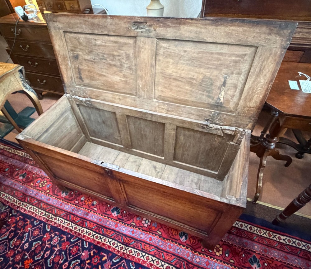 An antique oak coffer featuring a hinged rectangular top, two recessed front panels, and a central iron keyhole escutcheon resting on short block feet. View III