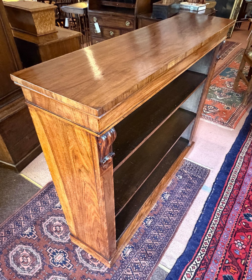 An early nineteenth-century open walnut bookcase featuring three shelves and carved corbels on the side stiles. View IV