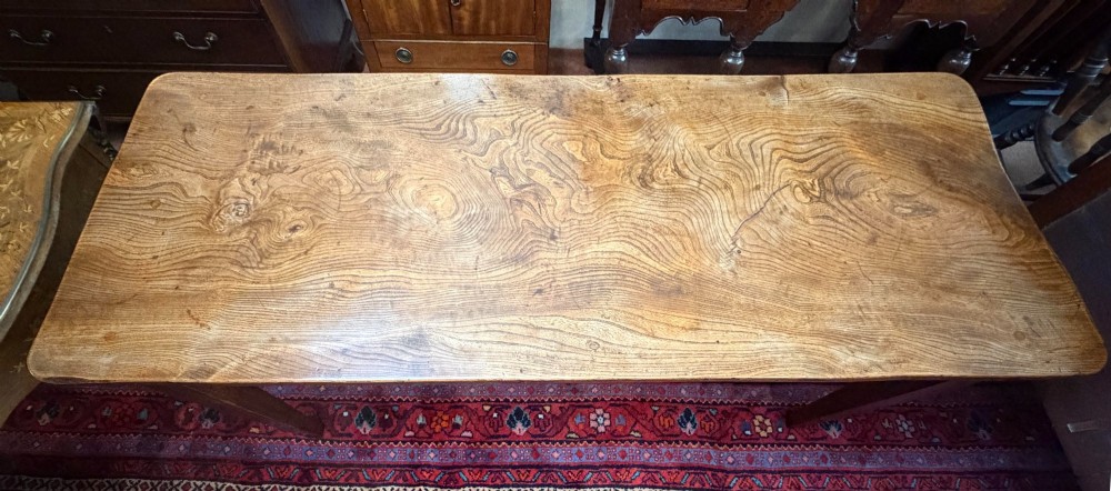 A rectangular antique wooden farmhouse table featuring a highly figured timber grain top supported by four square tapered legs. View II