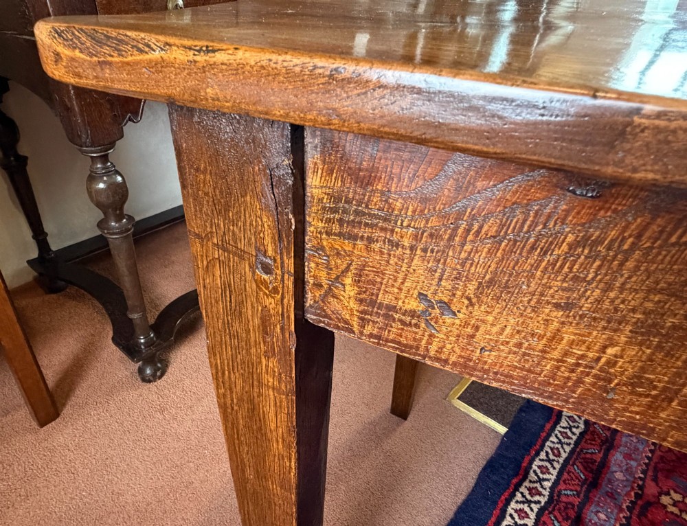 A rectangular antique wooden farmhouse table featuring a highly figured timber grain top supported by four square tapered legs. View V