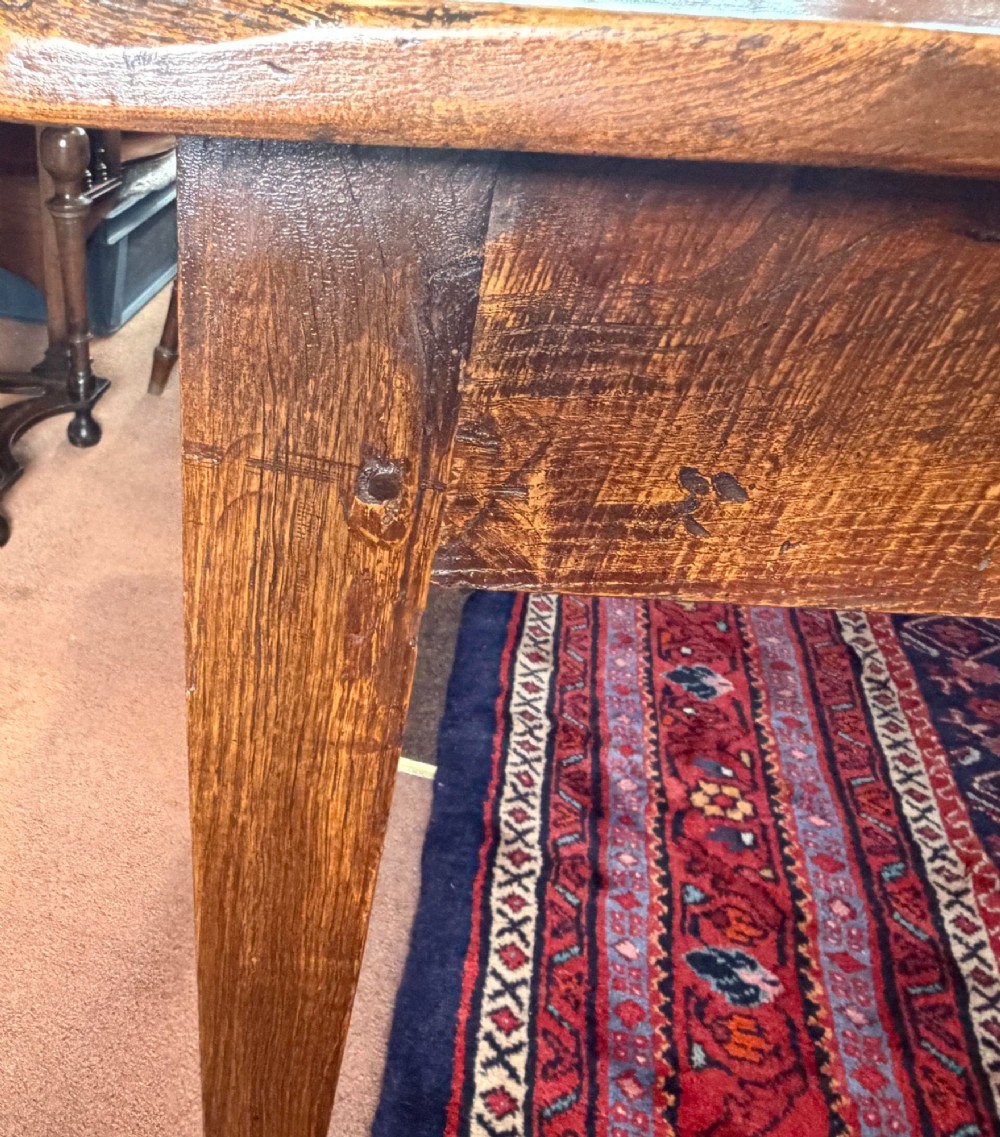 A rectangular antique wooden farmhouse table featuring a highly figured timber grain top supported by four square tapered legs. View VI