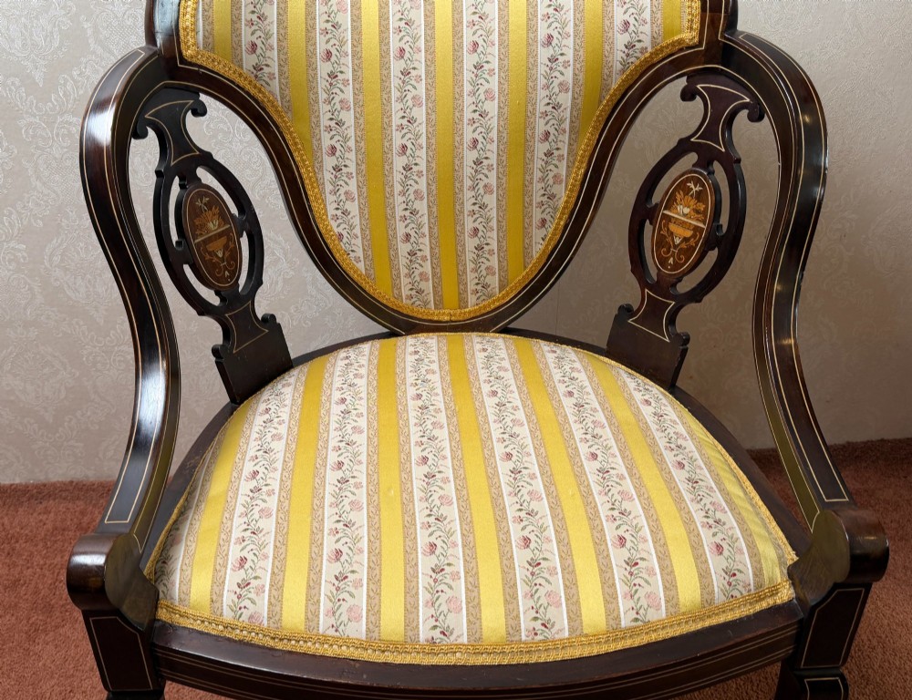 Late 19th century mahogany armchair featuring decorative bone and boxwood urn marquetry, curved arms, and yellow striped floral upholstery. View II