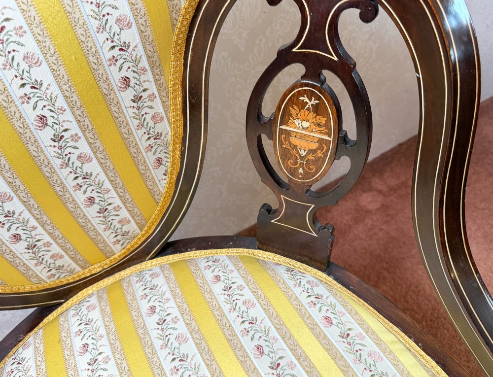 Late 19th century mahogany armchair featuring decorative bone and boxwood urn marquetry, curved arms, and yellow striped floral upholstery. View III