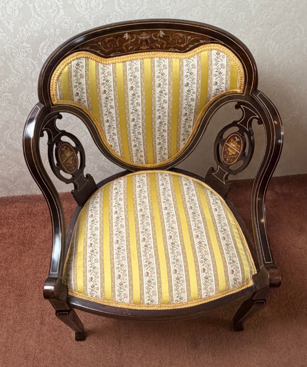 Late 19th century mahogany armchair featuring decorative bone and boxwood urn marquetry, curved arms, and yellow striped floral upholstery. View IV
