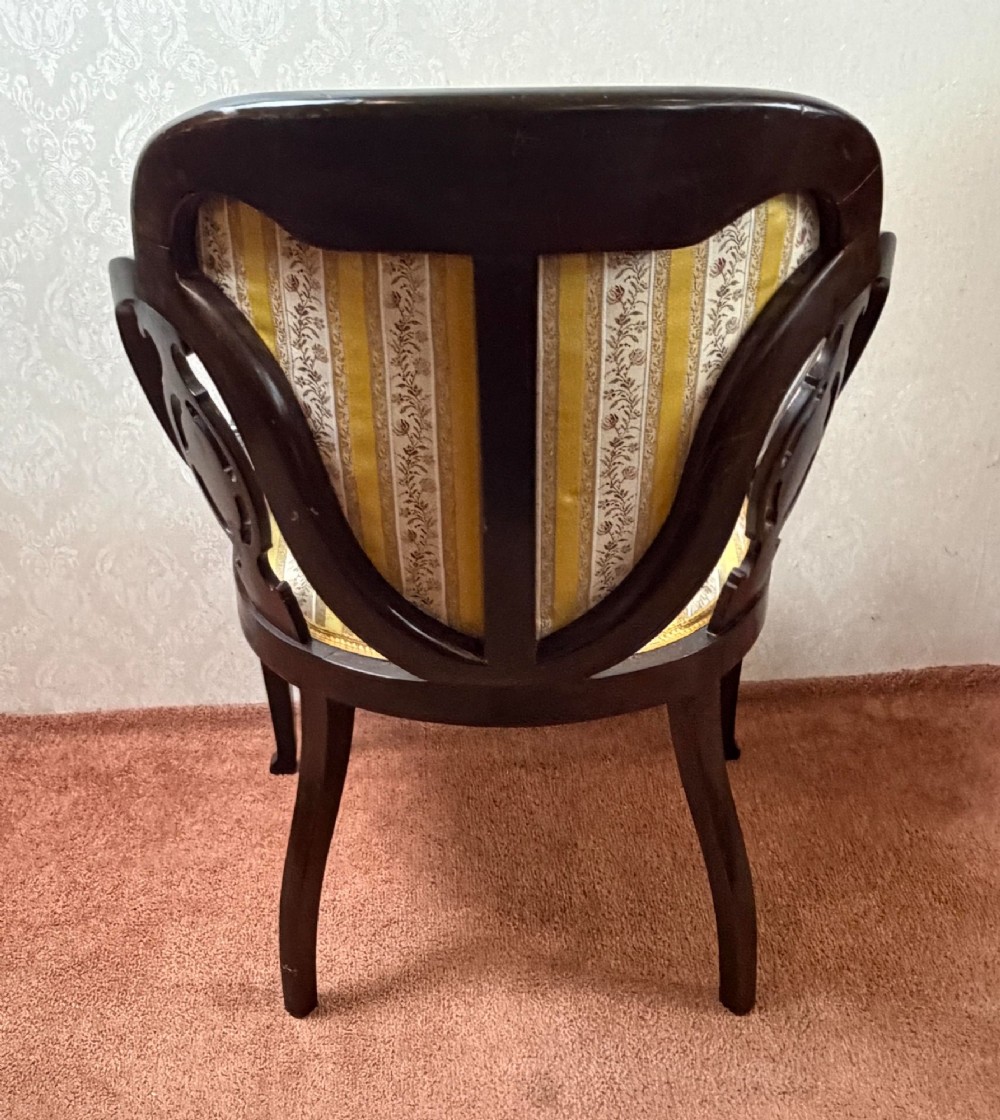 Late 19th century mahogany armchair featuring decorative bone and boxwood urn marquetry, curved arms, and yellow striped floral upholstery. View V
