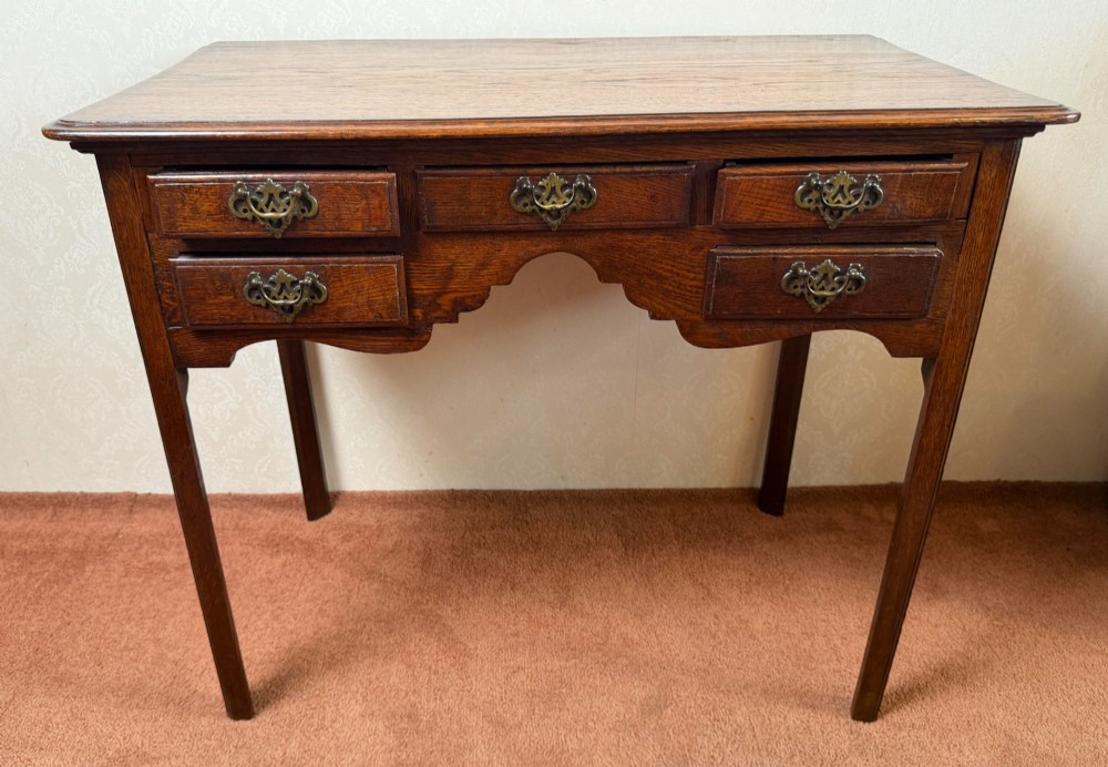 An 18th-century Georgian oak side table featuring five drawers, a central shaped apron, brass handles, and four straight legs. View II
