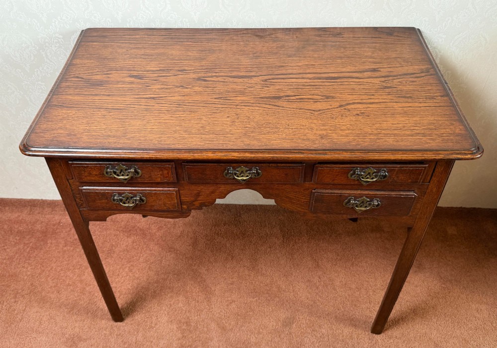 An 18th-century Georgian oak side table featuring five drawers, a central shaped apron, brass handles, and four straight legs. View IV
