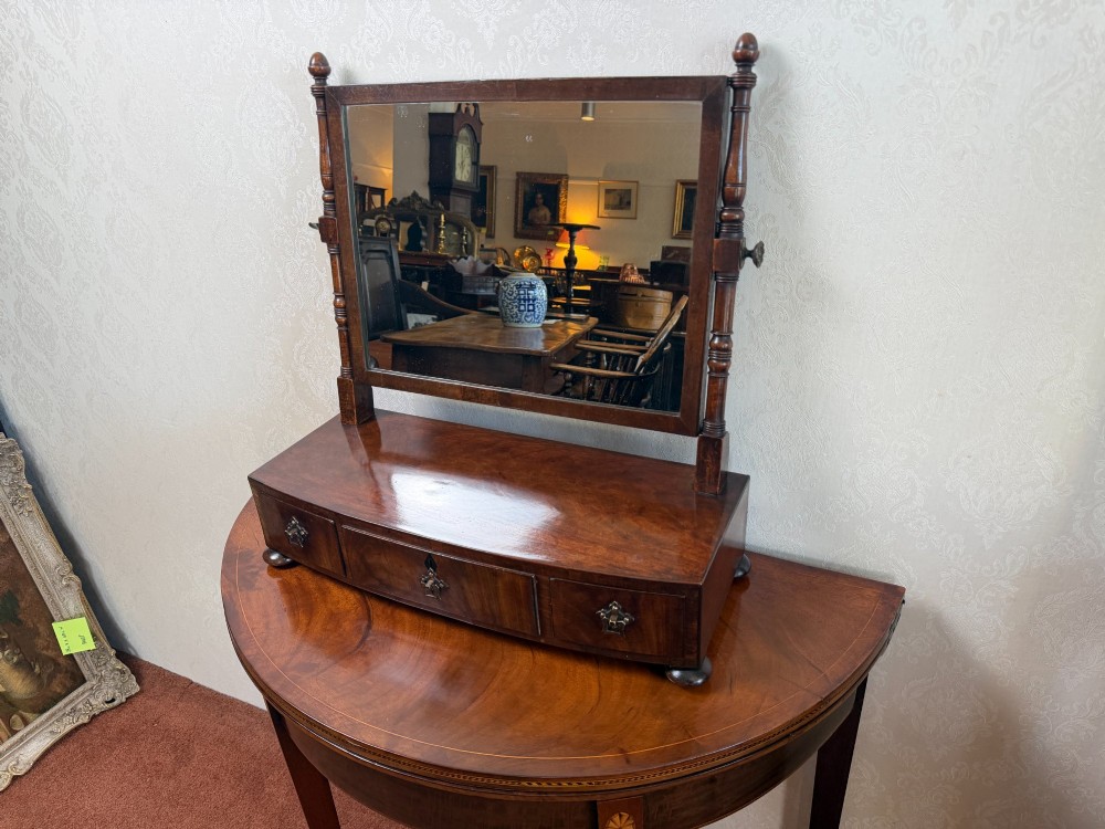 An early nineteenth-century mahogany box dressing mirror with a rectangular adjustable frame set above three drawers on small ball feet.
