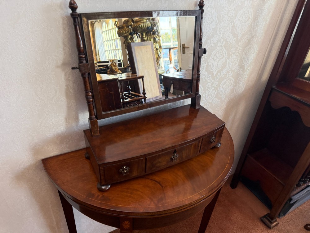 An early nineteenth-century mahogany box dressing mirror with a rectangular adjustable frame set above three drawers on small ball feet. View II