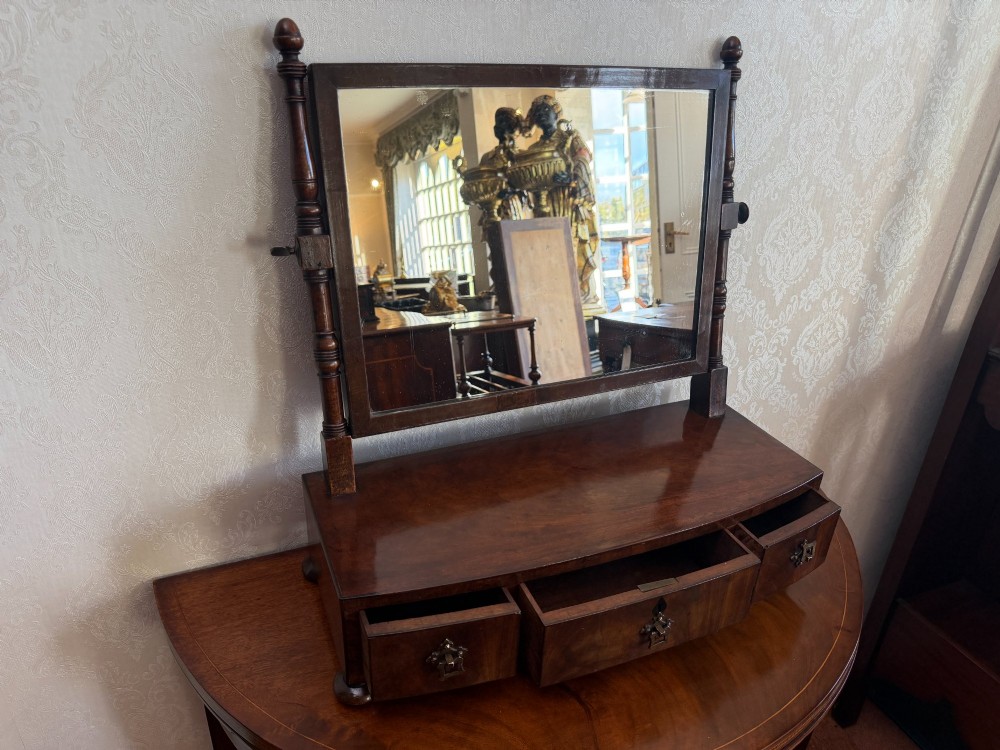 An early nineteenth-century mahogany box dressing mirror with a rectangular adjustable frame set above three drawers on small ball feet. View V