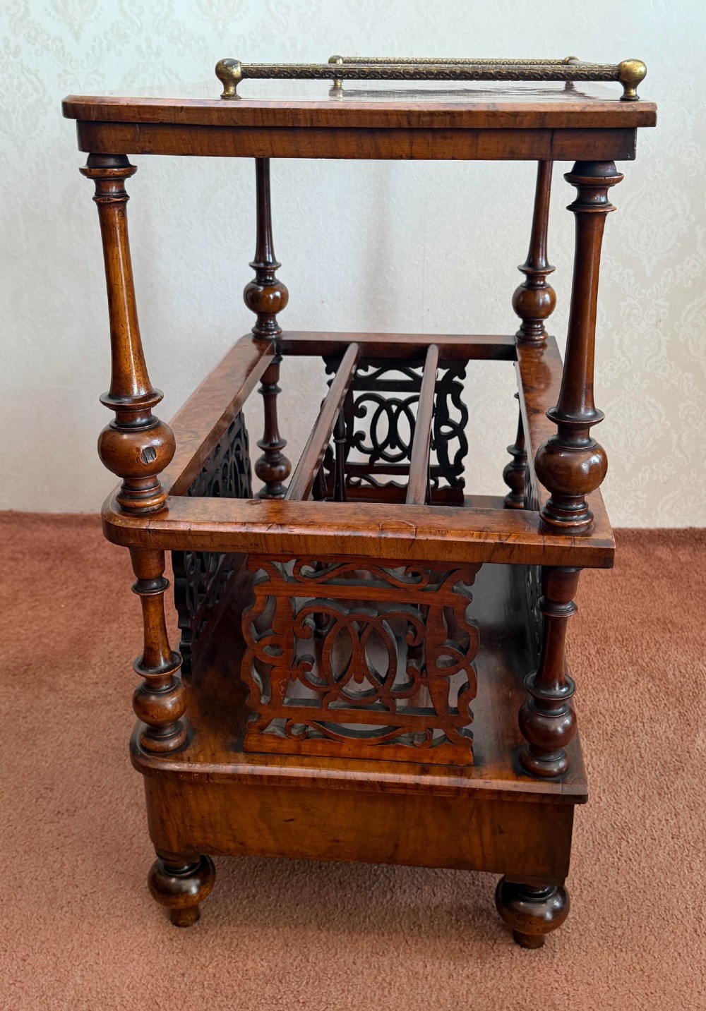 A Victorian burr walnut music Canterbury featuring a upper brass gallery rail, open vertical partitions with fretwork panels, turned corner columns, and a base drawer. View IV