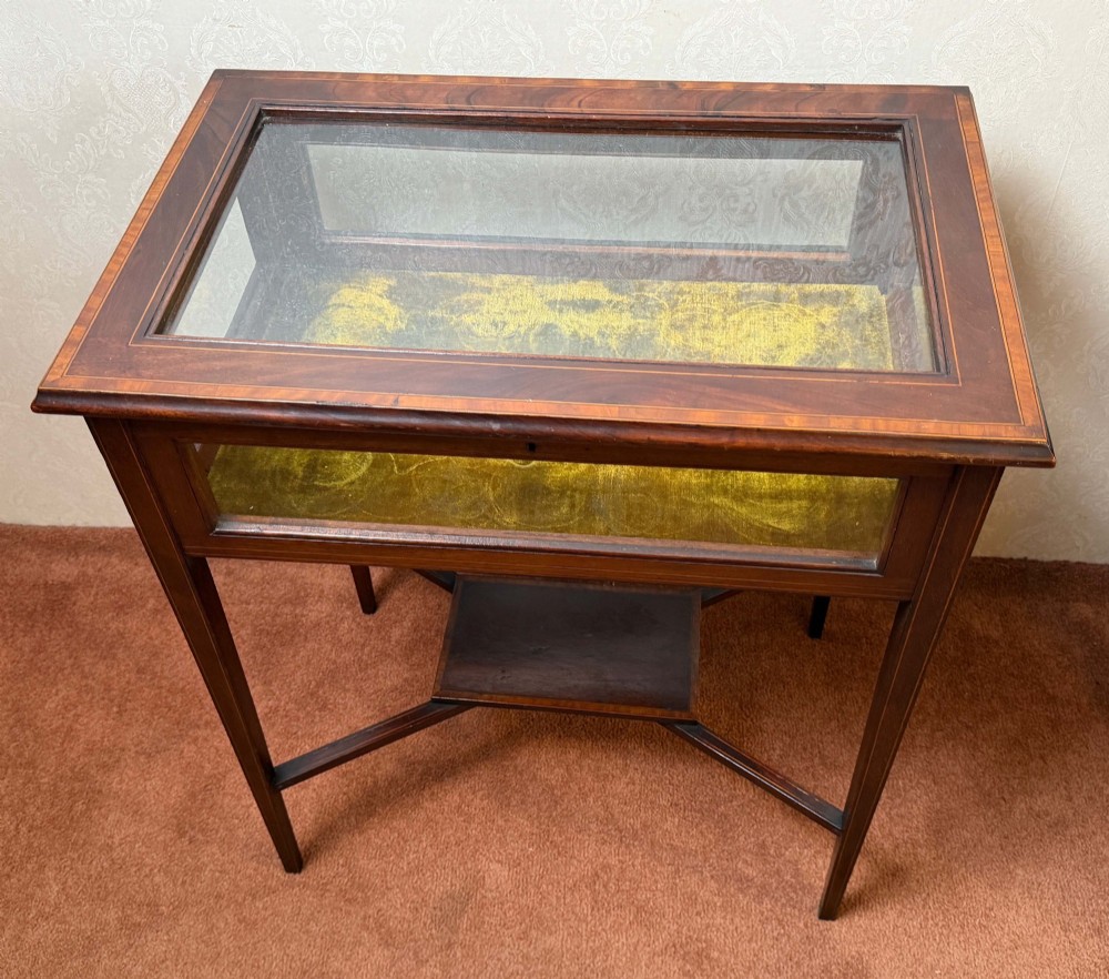 A late 19th-century mahogany bijouterie table featuring glass top and side panels, a yellow velvet-lined display interior, tapered square legs, and an X-shaped stretcher with a central undertier. View II