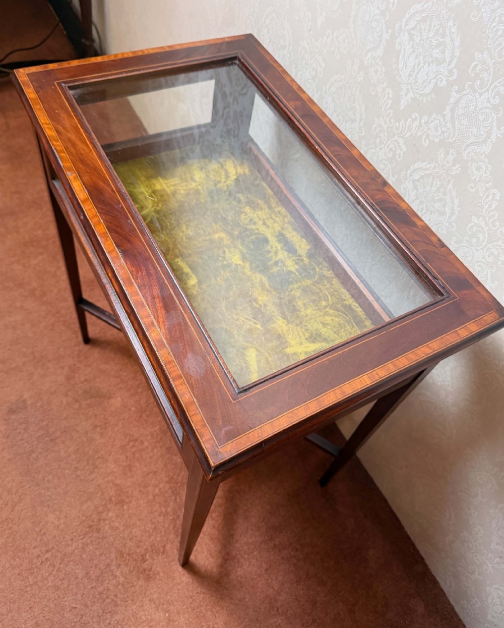 A late 19th-century mahogany bijouterie table featuring glass top and side panels, a yellow velvet-lined display interior, tapered square legs, and an X-shaped stretcher with a central undertier. View IV